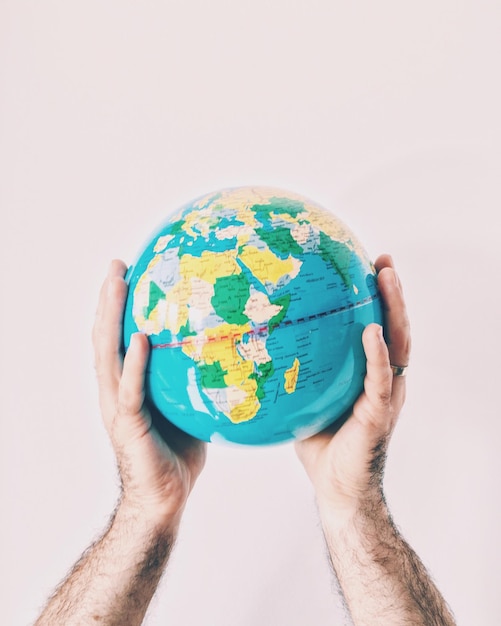 Mão recortada segurando globo contra fundo branco
