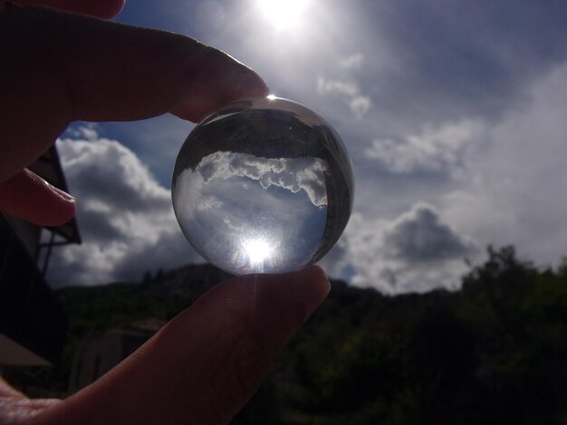 Foto mão recortada segurando mármore contra o céu