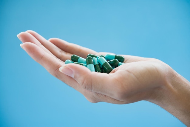 Mão recortada segurando medicamentos em fundo azul