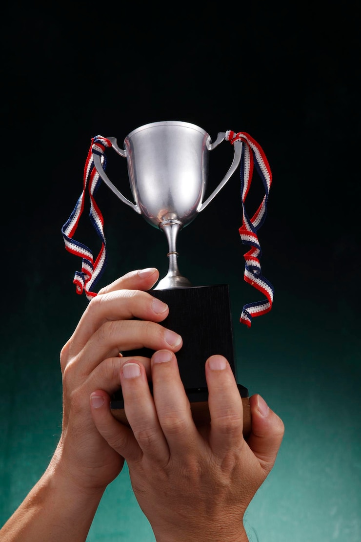 Foto mão recortada segurando troféu contra fundo verde