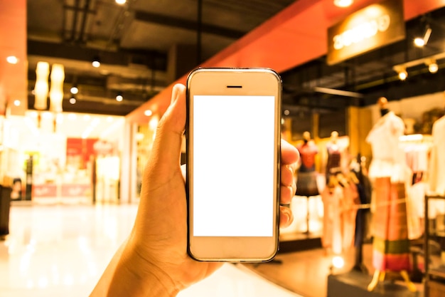Foto mão recortada segurando um telefone móvel em branco em um shopping