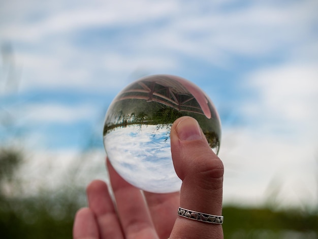 Mão recortada segurando uma bola de cristal contra o céu