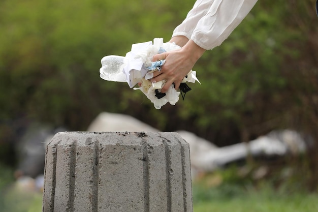 Foto mão recortada segurando uma flor branca contra um fundo desfocado