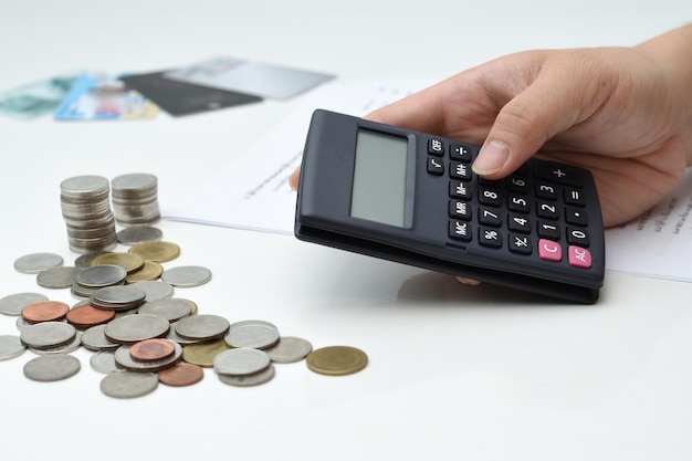 Mão recortada usando calculadora enquanto conta moedas
