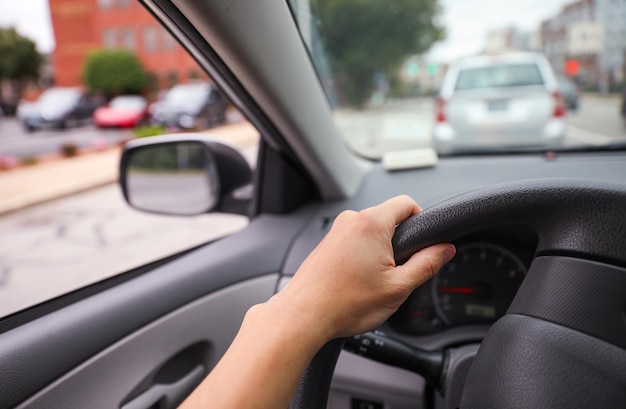 mão segura o volante de um carro, simbolizando uma direção segura e controlada, com foco na responsabilidade