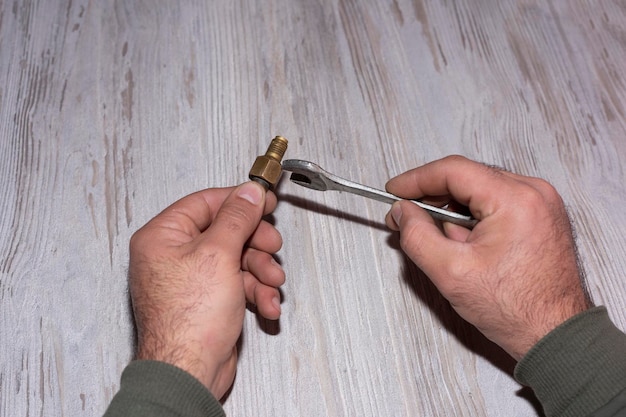 Foto mão segura uma chave de fenda e uma chave de fenda em uma porta de madeira a mão de um homem fecha