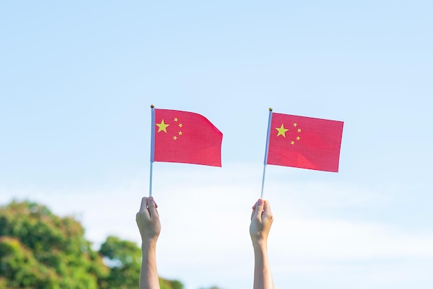 Mão segurando a bandeira da China no fundo do céu azul Dia Nacional da República Popular da China Dia do feriado da nação pública e conceitos de celebração feliz