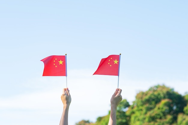 Mão segurando a bandeira da china no fundo do céu azul. dia nacional da república popular da china, dia público do feriado da nação e conceitos de celebração feliz