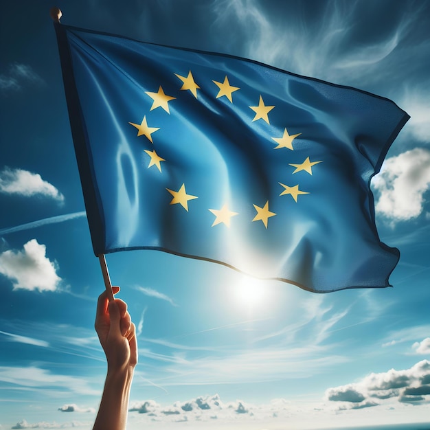 Mão segurando a bandeira da União Europeia contra um céu azul nublado
