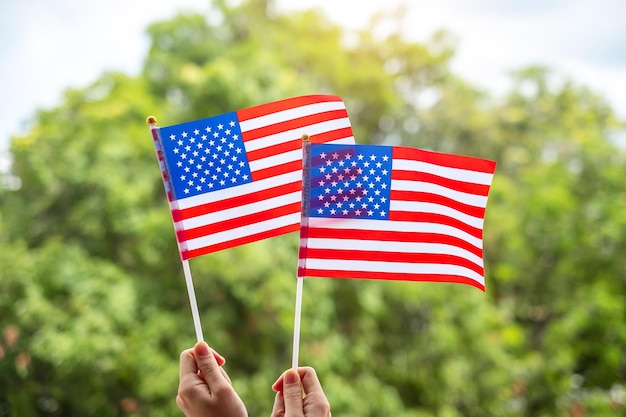 Mão segurando a bandeira dos Estados Unidos da América em fundo verde, feriado dos EUA do Memorial da Independência dos Veteranos, quatro de julho e conceito do Dia do Trabalho