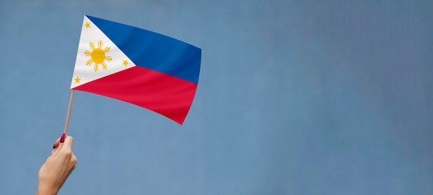 Foto mão segurando a bandeira filipina