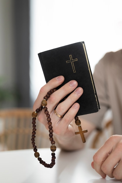 Mão segurando a Bíblia e o Rosário