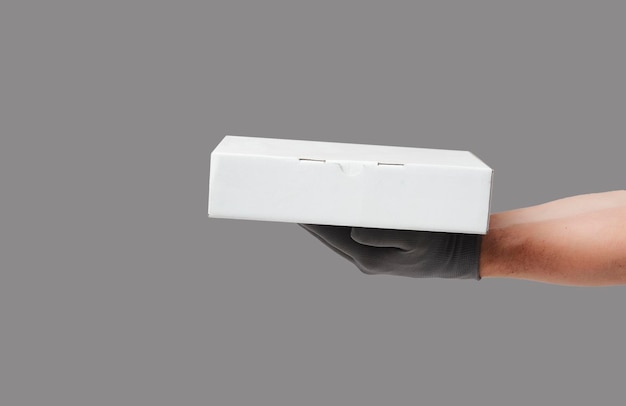 Mão segurando a caixa de papelão sobre fundo cinza com espaço de cópia Conceito de serviço de entrega e envio closeup de caixa de pizza de entrega de mão