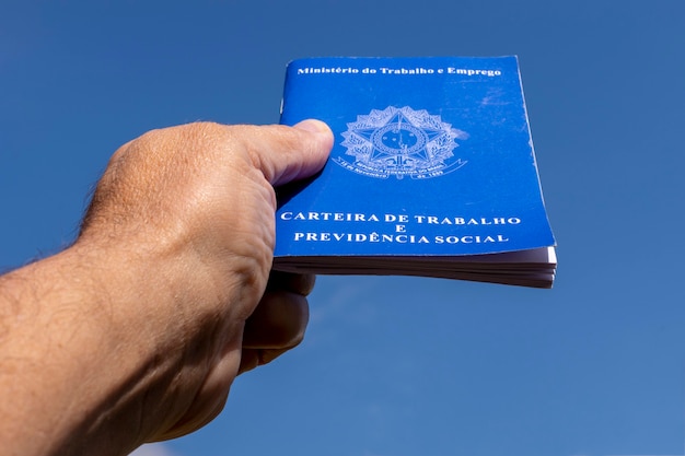 Foto mão segurando a carteira de trabalho brasileira apontando para o céu. conceito de aumento de salário.