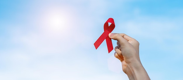 Mão segurando a fita vermelha para apoiar as pessoas que vivem e doenças. Conceito de saúde e sexo seguro. Dezembro Dia Mundial da AIDS e mês da Conscientização sobre o Câncer do Mieloma Múltiplo