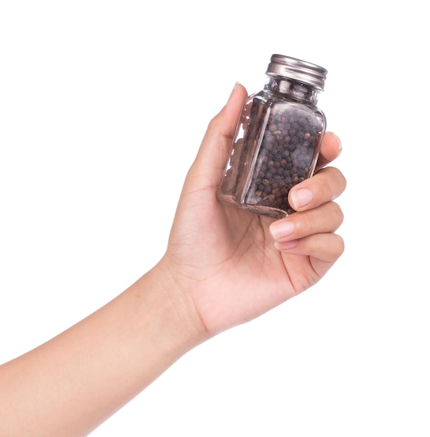 mão segurando a garrafa de pimenta preta e sementes de coentro isoladas no fundo branco