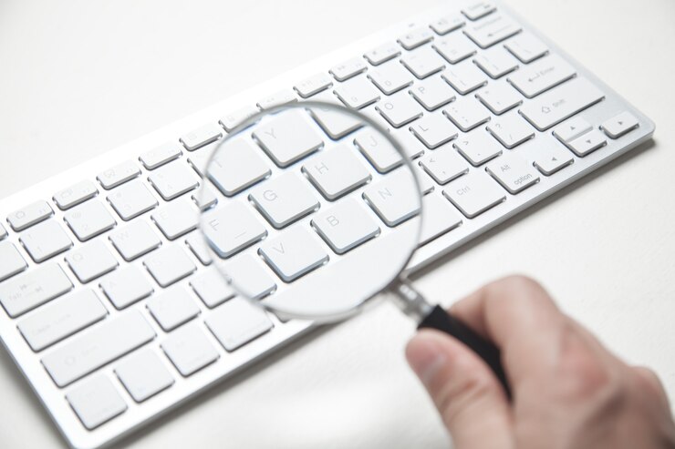 Foto mão segurando a lupa com o teclado do computador pesquisando na internet
