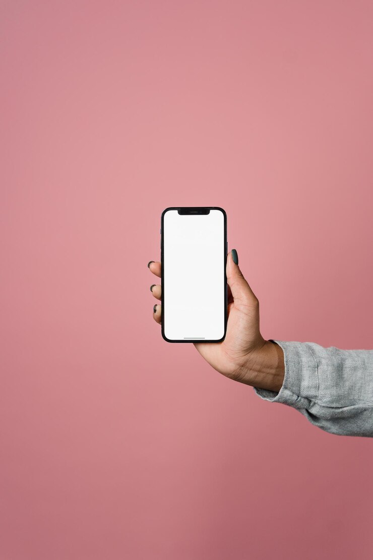 Foto mão segurando a maquete do smartphone com fundo rosa