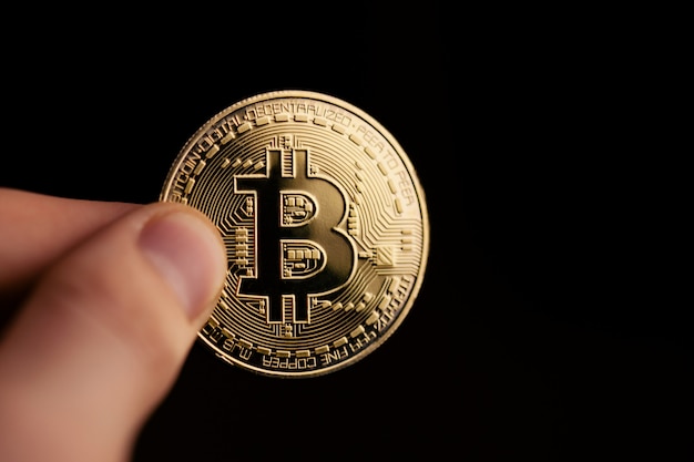 Foto mão segurando a moeda de bitcoin dourada