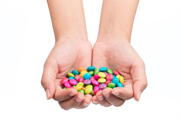 mão segurando a pilha de doces revestidos de chocolate coloridos isolados no fundo branco
