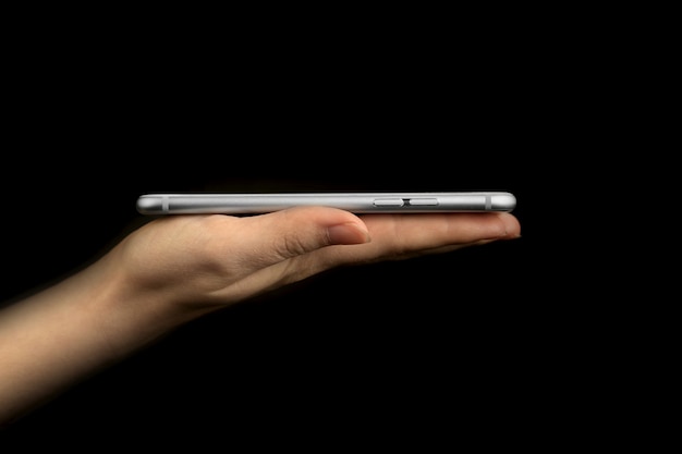 Mão segurando a vista lateral do telefone móvel para apresentação, foto de estúdio, modelo ou maquete em uma foto de fundo preto