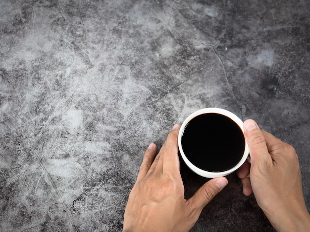 Mão segurando a vista superior de fundo escuro de xícara de café preto