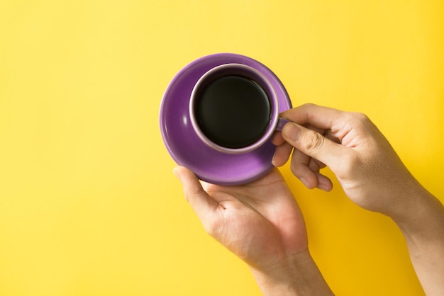 Foto mão segurando a xícara de café no fundo amarelo