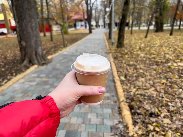 Mão segurando a xícara de café no fundo do parque outono