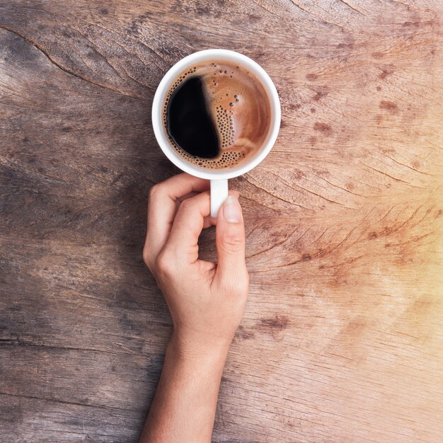 Mão segurando a xícara de café