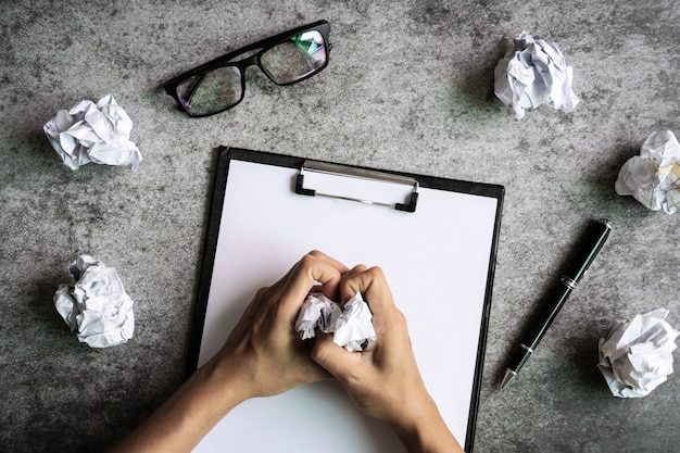 Mão segurando amassado bolas de papel com óculos