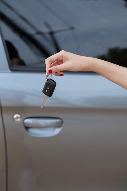Foto mão segurando as chaves do carro com carro no fundo