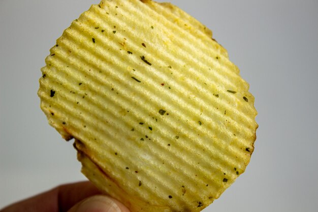 Mão segurando batatas fritas isoladas em branco.