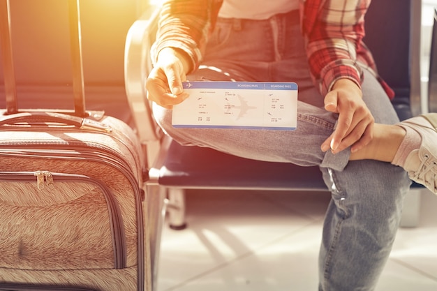 Mão segurando bilhetes ou cartão de embarque. Viagem aérea no portão esperando no terminal.