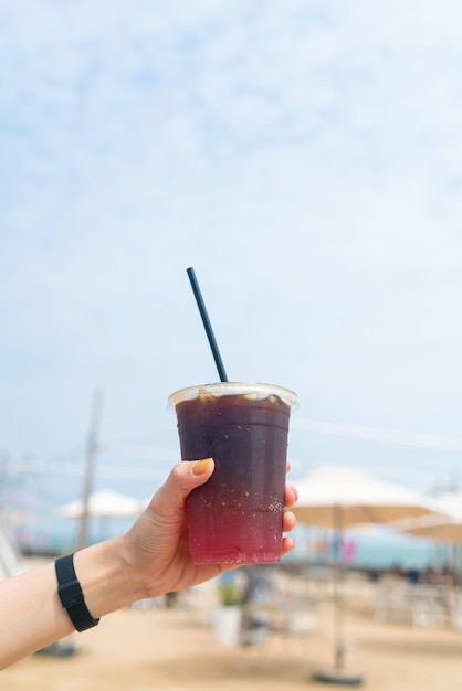 Mão segurando café americano gelado com espaço de cópia