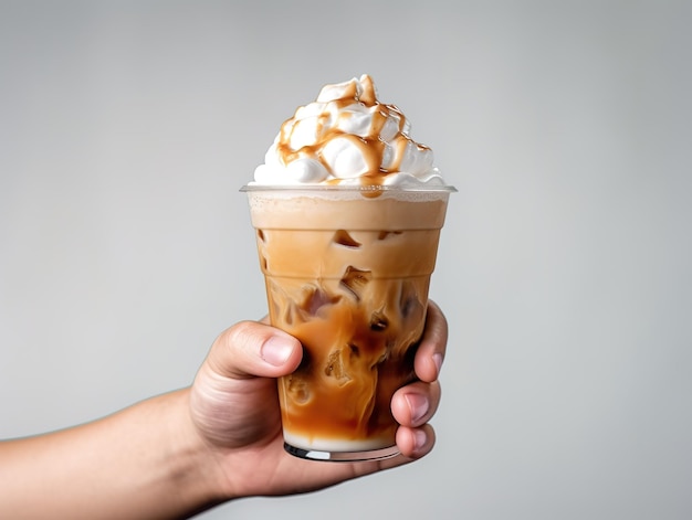 Mão segurando café com leite gelado com chantilly e cobertura de caramelo