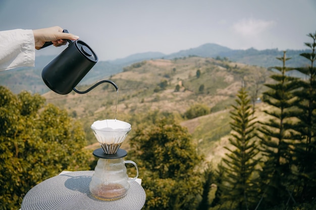Mão segurando café com vista para montanhas borradas no conceito de espaço de cópia da manhã