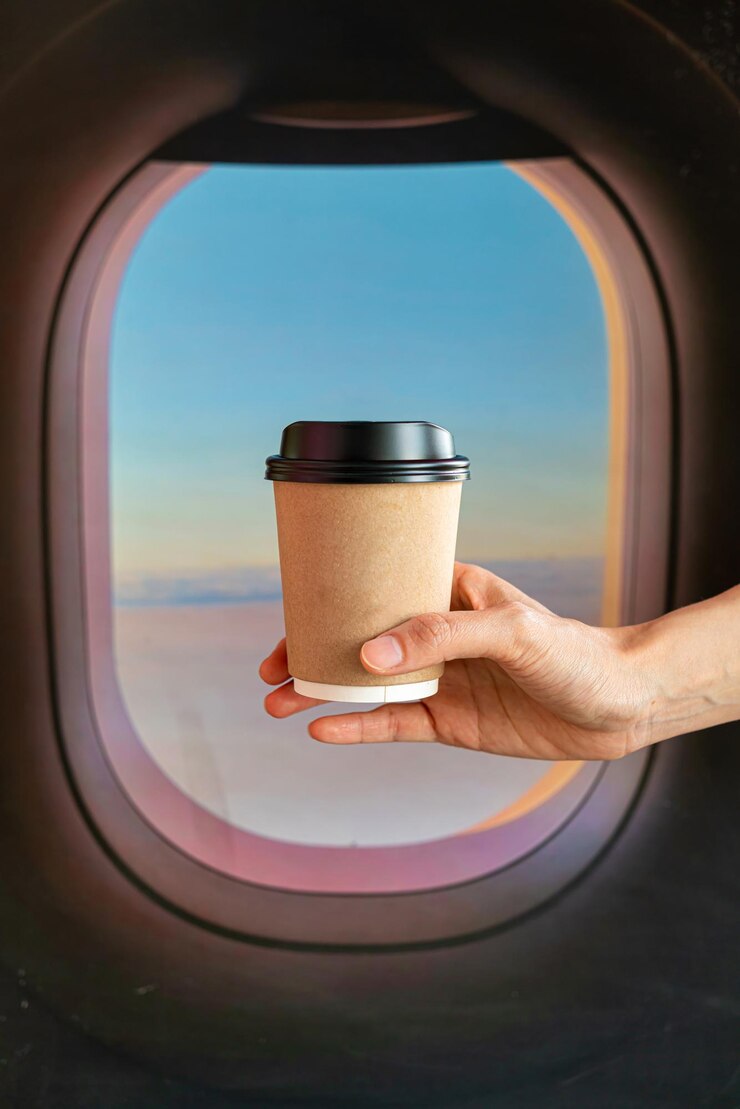Foto mão segurando café quente em vidro para viagem com fundo de janela de avião