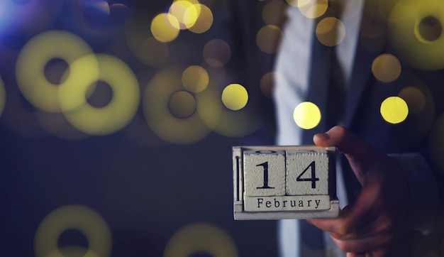 Foto mão segurando cubos de madeira com o conceito de calendário de data de 14 de fevereiro de são valentim