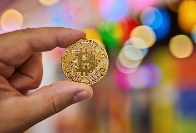 Mão segurando dinheiro virtual Bitcoin dourado