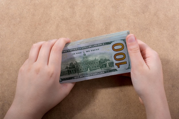 Mão segurando dólar americano isolado em fundo de madeira