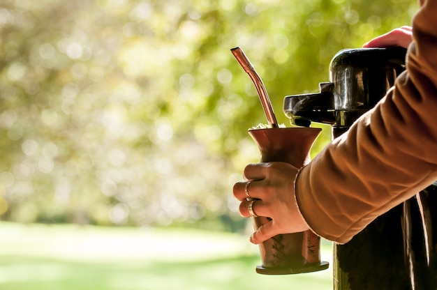 Foto mão segurando e servindo chá mate de chimarrao chá típico do sul do brasil