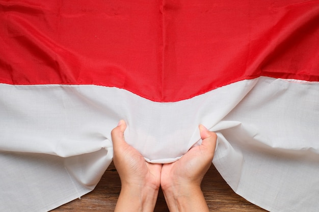 Mão segurando e tocando a bandeira nacional da Indonésia vermelha e branca, conceito do dia da independência da Indonésia