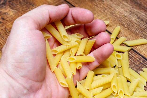 Mão segurando espaguete, macarrão, trigo duro fundo de massa italiana close-up