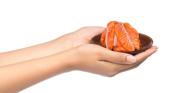 mão segurando fatia de bife de peixe vermelho salmão cru fresco em um prato de madeira isolado em um fundo branco