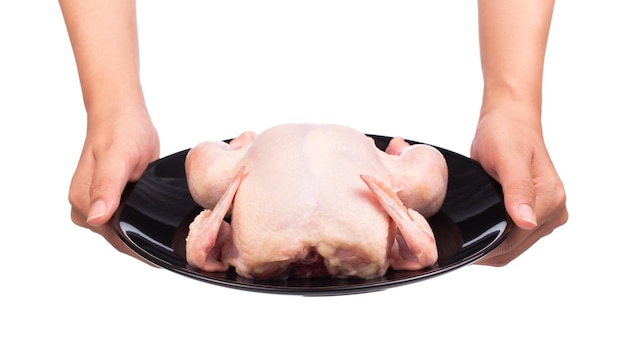 mão segurando frango cru em um prato preto isolado no fundo branco