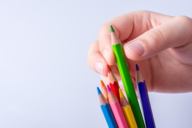 Mão segurando lápis de cor colocados sobre um fundo branco
