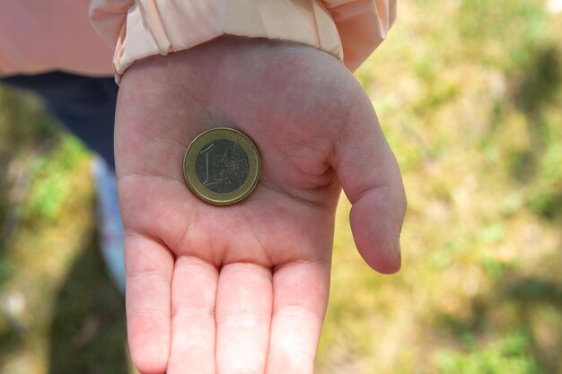 Mão segurando moedas de euro na rua