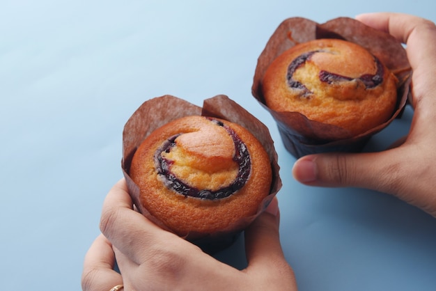 Mão segurando muffins de mirtilo na mesa