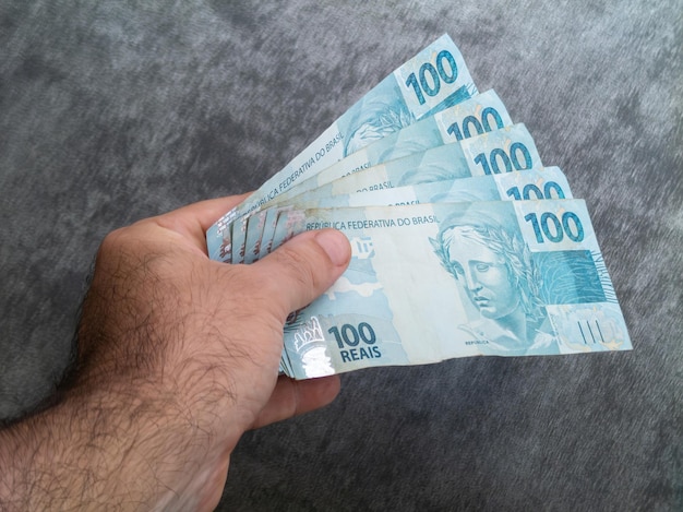 Mão segurando notas de cem reais brasileiras Conceito de finanças