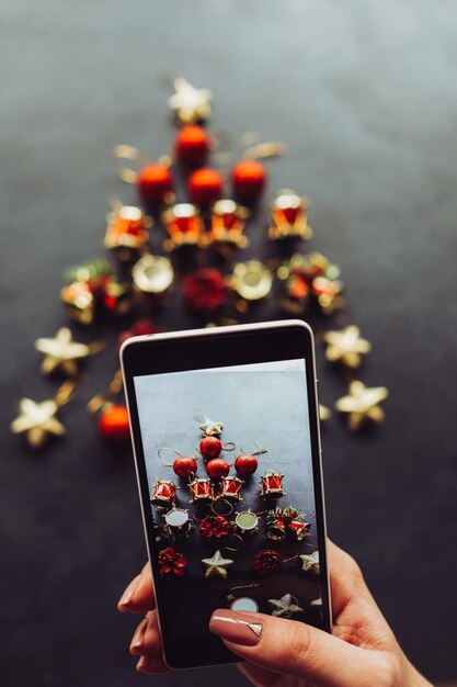 Mão segurando o celular para fazer uma foto da decoração da árvore de Natal Blogger postando imagens para o conceito de mídia social